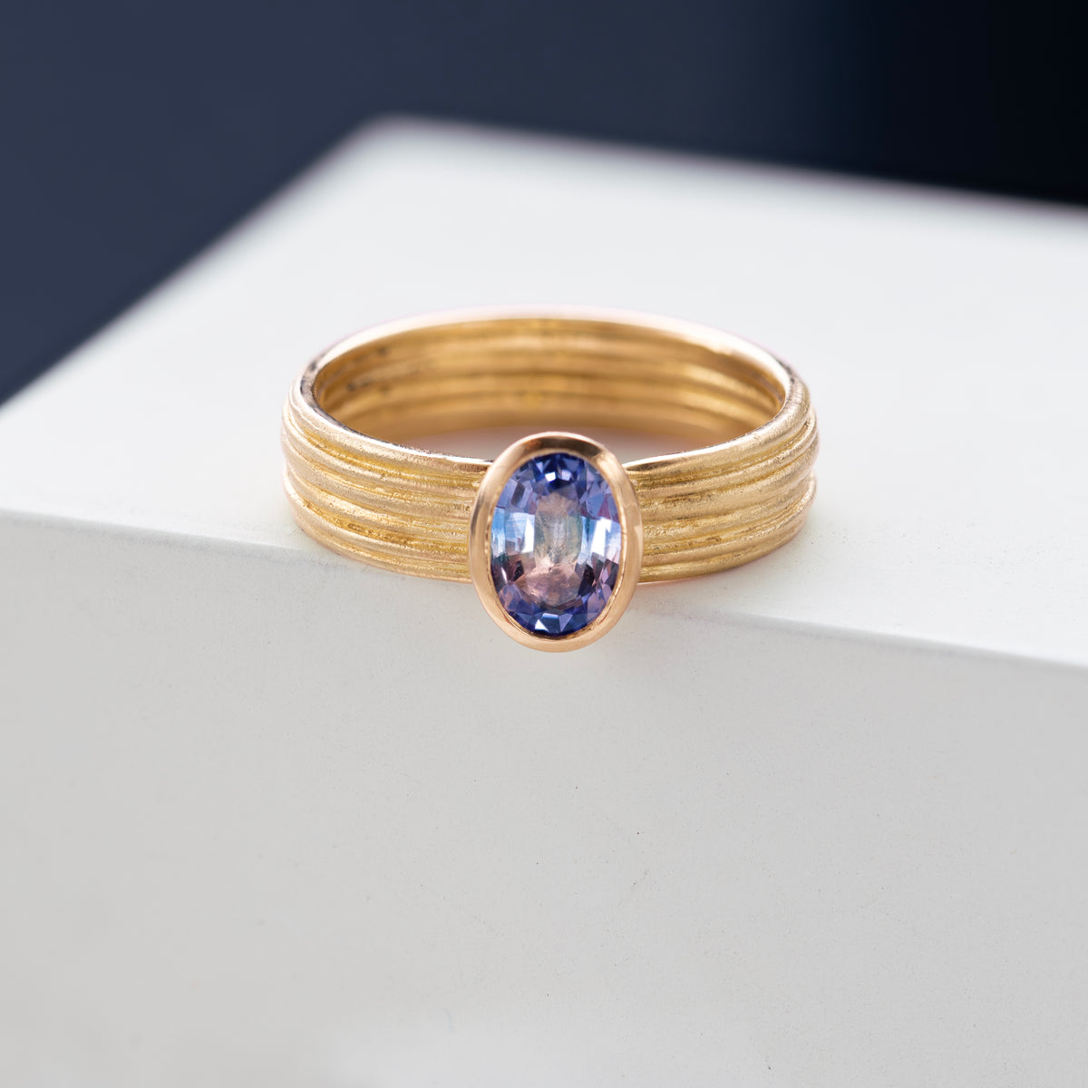 Tri-Colour Sapphire and 18ct Gold Ring shown against a styled backdrop.