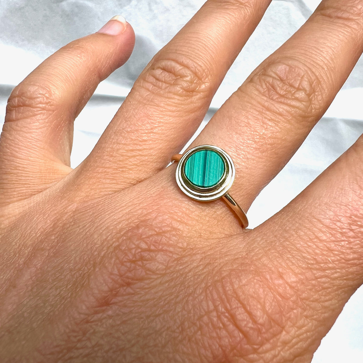 Ascent Gold Ring with Malachite Stone worn on a hand, showing the striped green malachite stone up close.