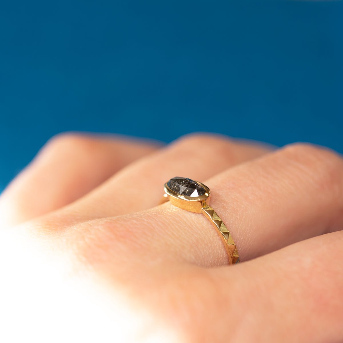 Close-up of the Eclipse 18ct Gold & Grey Oval Diamond Ring worn on a hand, showing the grey diamond's facets.