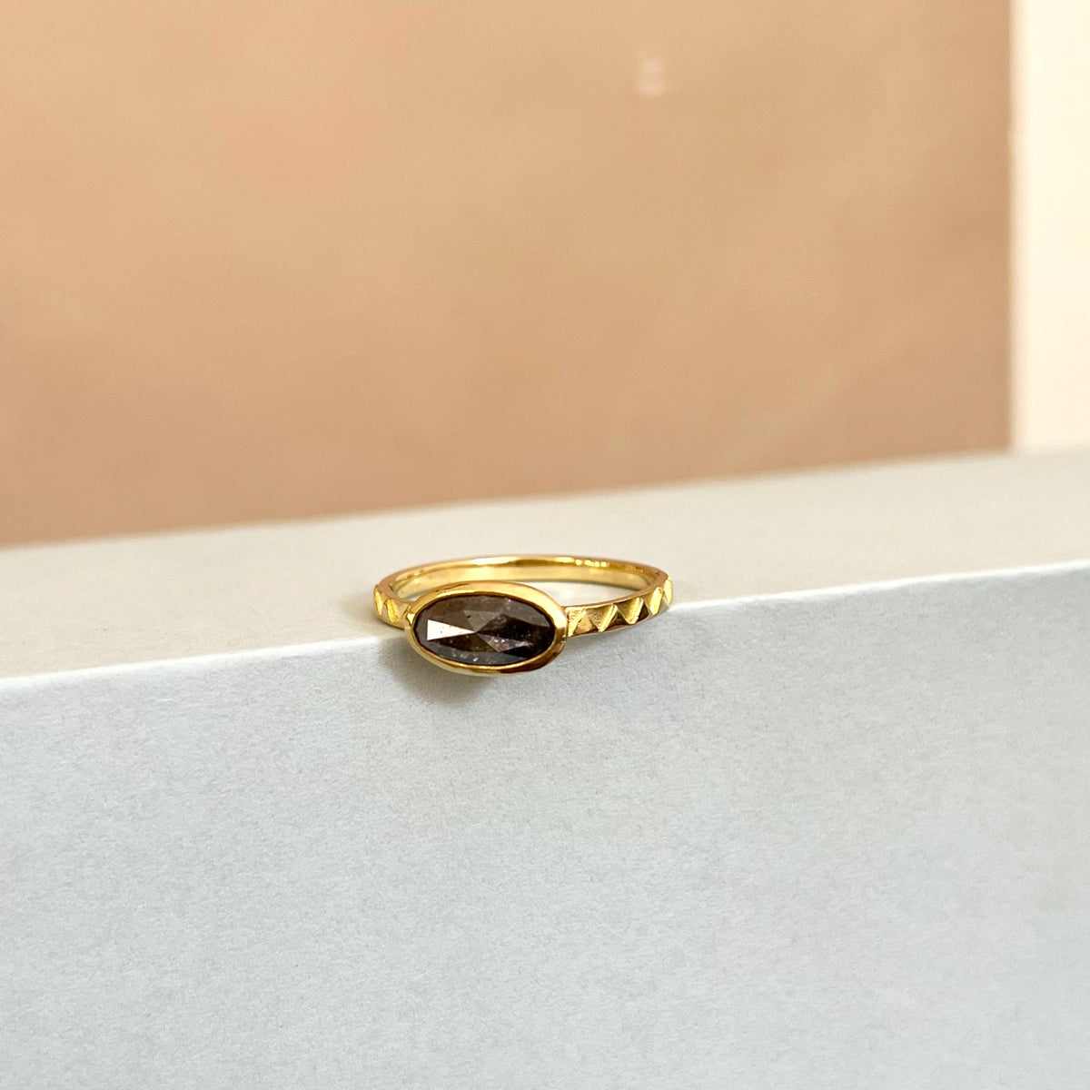 Eclipse 18ct Gold & Grey Oval Diamond Ring shown against a styled backdrop.
