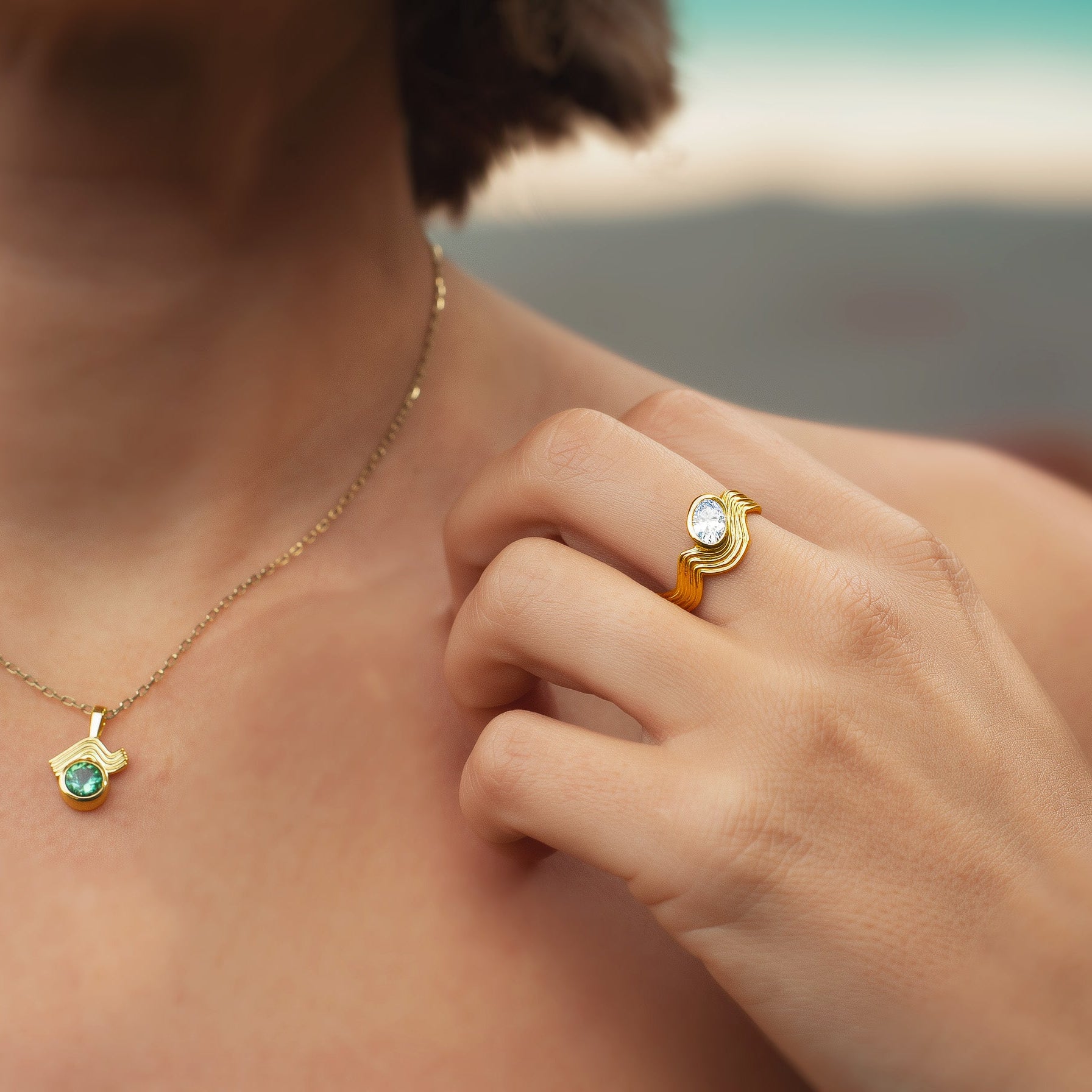 Model wearing the Oval Diamond Wave Ring on her hand, with a Zelda Cave pendant necklace softly visible in the background.