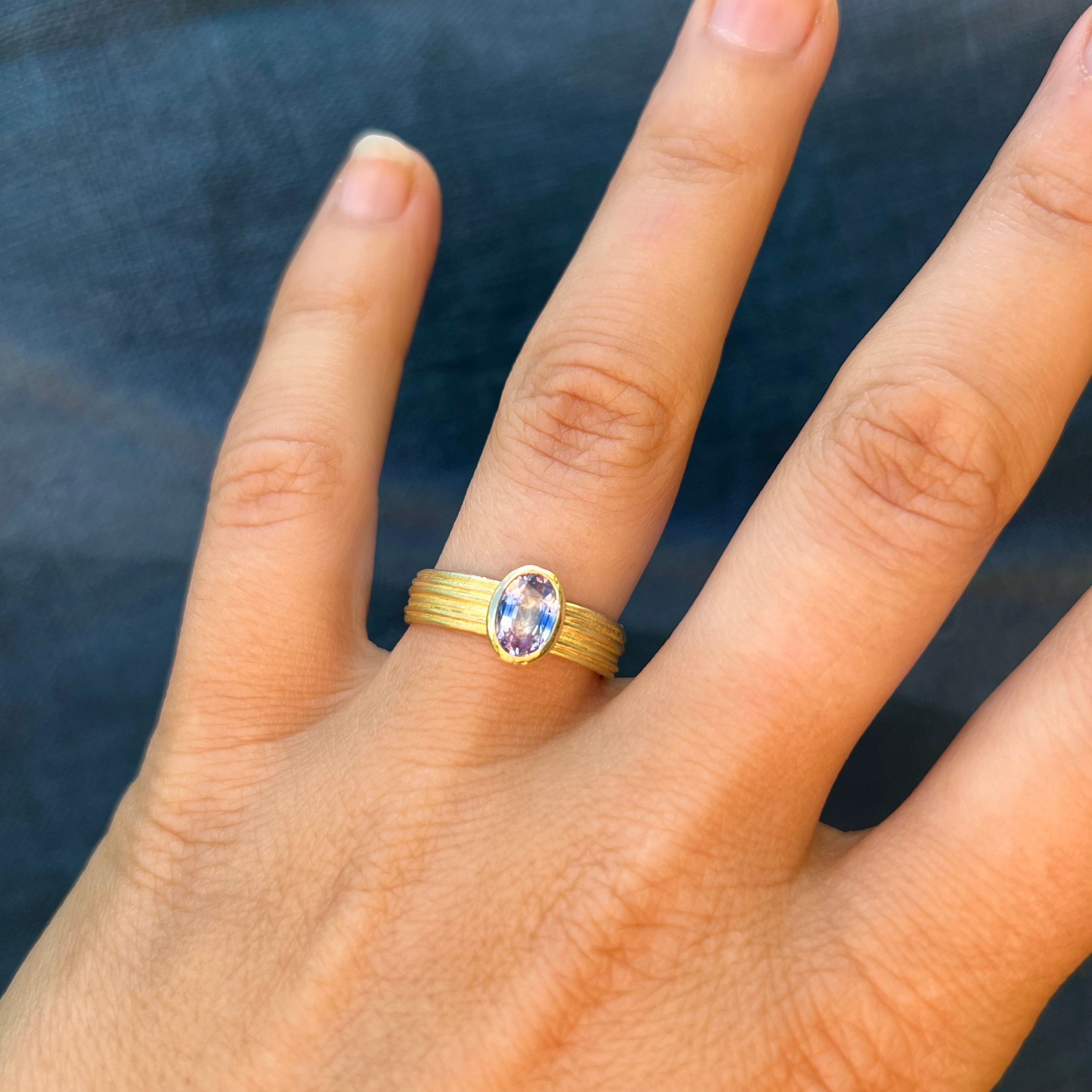 Tri-Colour Sapphire and 18ct Gold Ring worn on a hand, showing the sapphire's violet and blue tones.