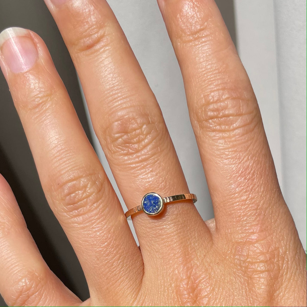 Scintilla Ring with Lapis Lazuli worn on a hand, showing the round lapis lazuli stone on a textured band.