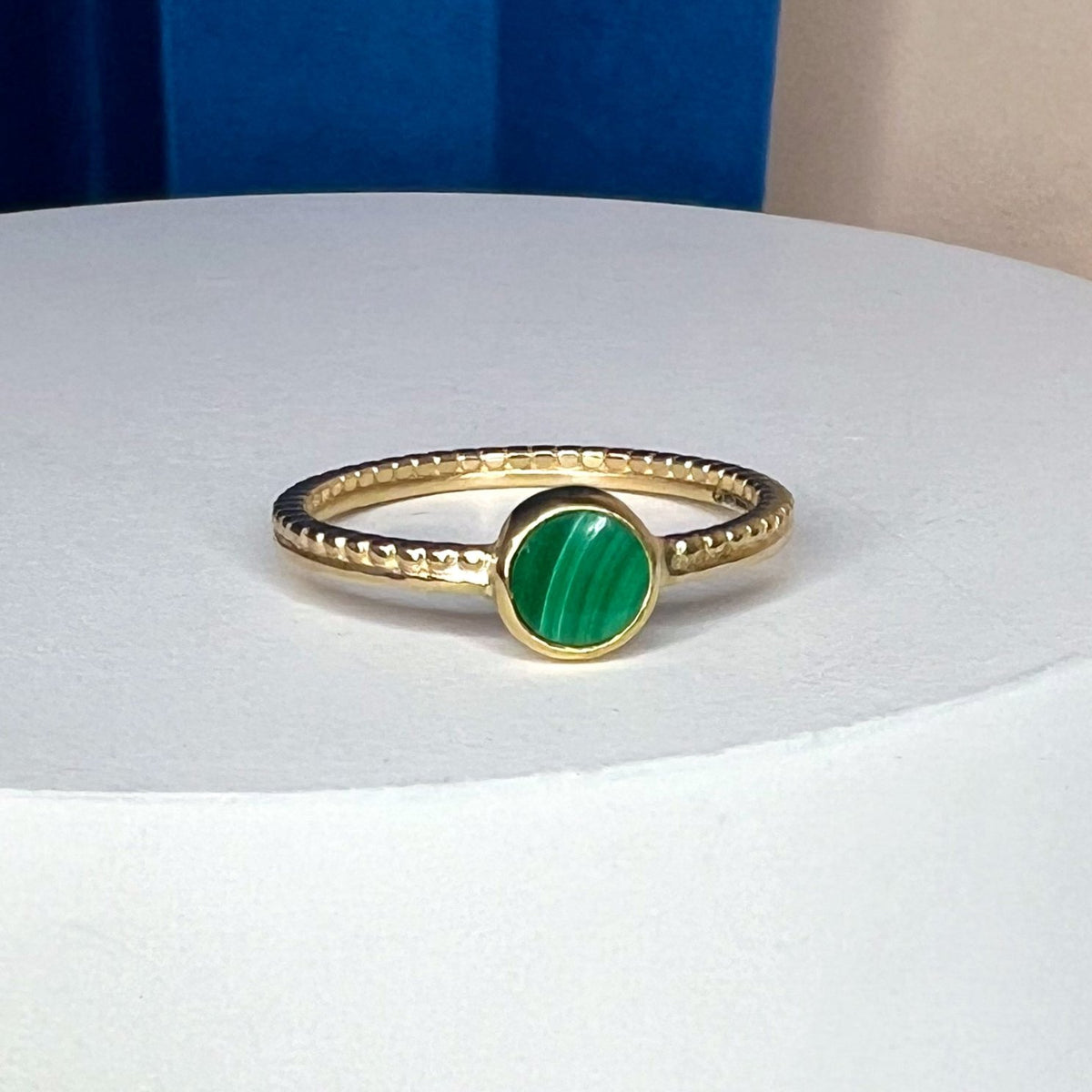 Gold ring with a textured band and a round malachite cabochon stone
